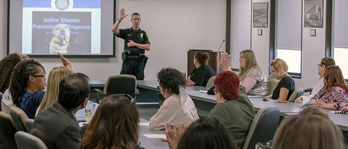 Interior classroom filled with attendees led by an officer at a podium in front of a slide projector