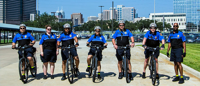Outdoor photo of seven Bike Patrol members lined up side by side, five of the seven members on patrol bikes