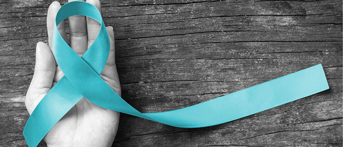 Grayscale image of a female hand with vivid Sexual Assault Awareness teal ribbon being held